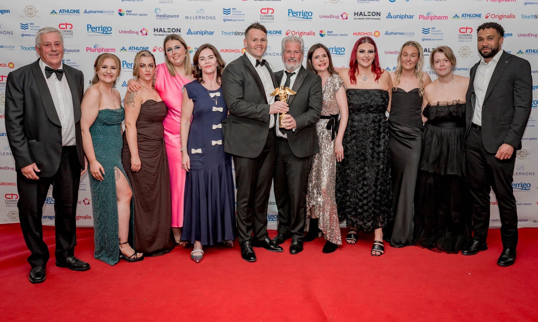 The Finnegan's Pharmacy team celebrating their Irish Pharmacy Awards win, holding the trophy